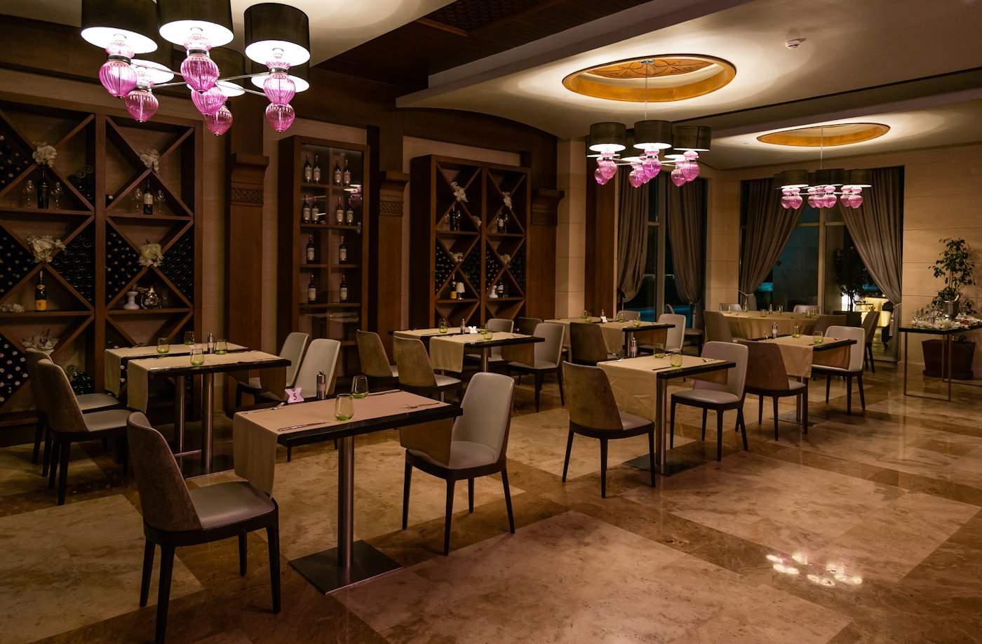 La salle du restaurant, tables dressées sous des lampes